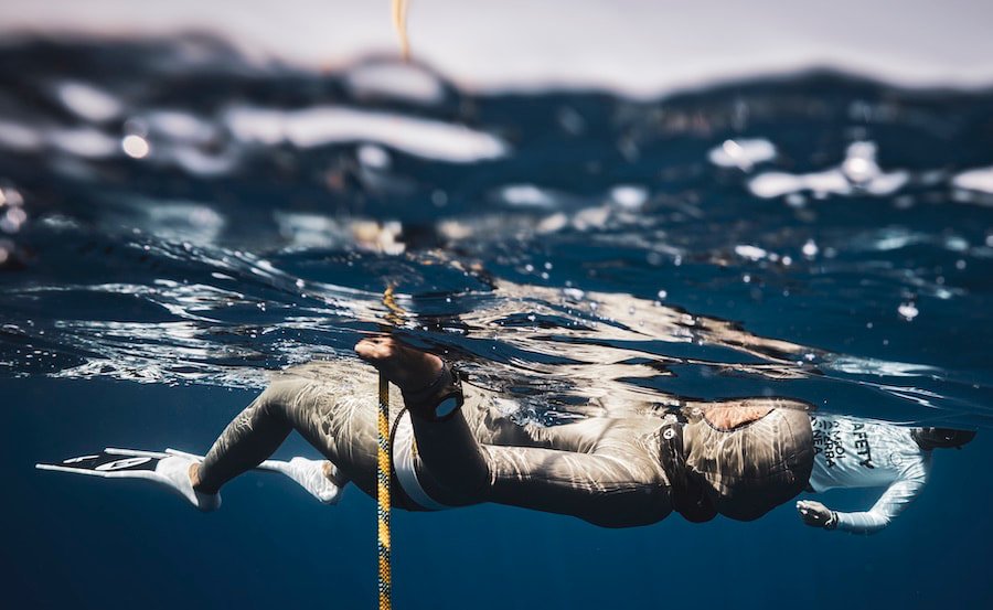 Freediver lying on water surface preparing for a dive, wearing Alchemy Neck Weight in Black